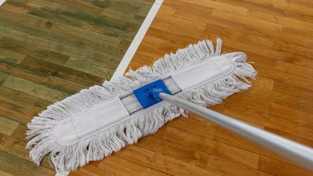 A mop cleaning a wooden sports court floor