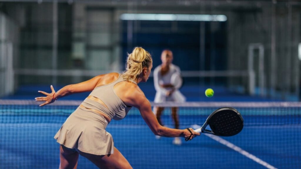 Two women playing padel on an indoor court