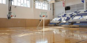 Brightly lit basketball court, new backboard, hoop.