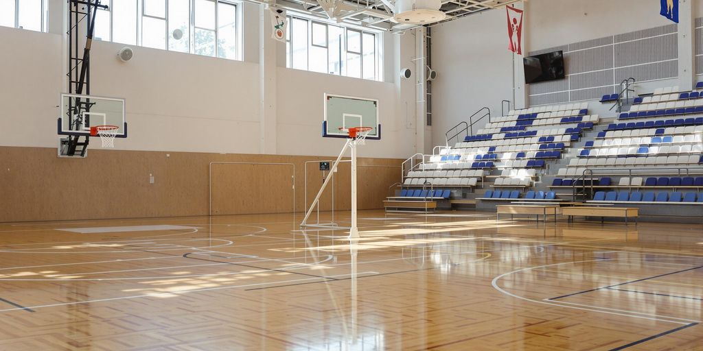 Brightly lit basketball court, new backboard, hoop.