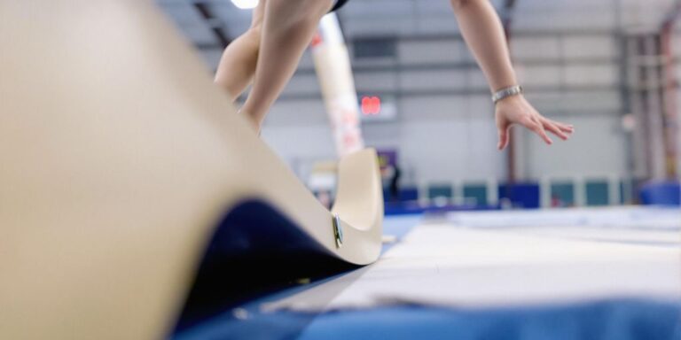 Gymnast mid-air, landing on a sprung floor system.