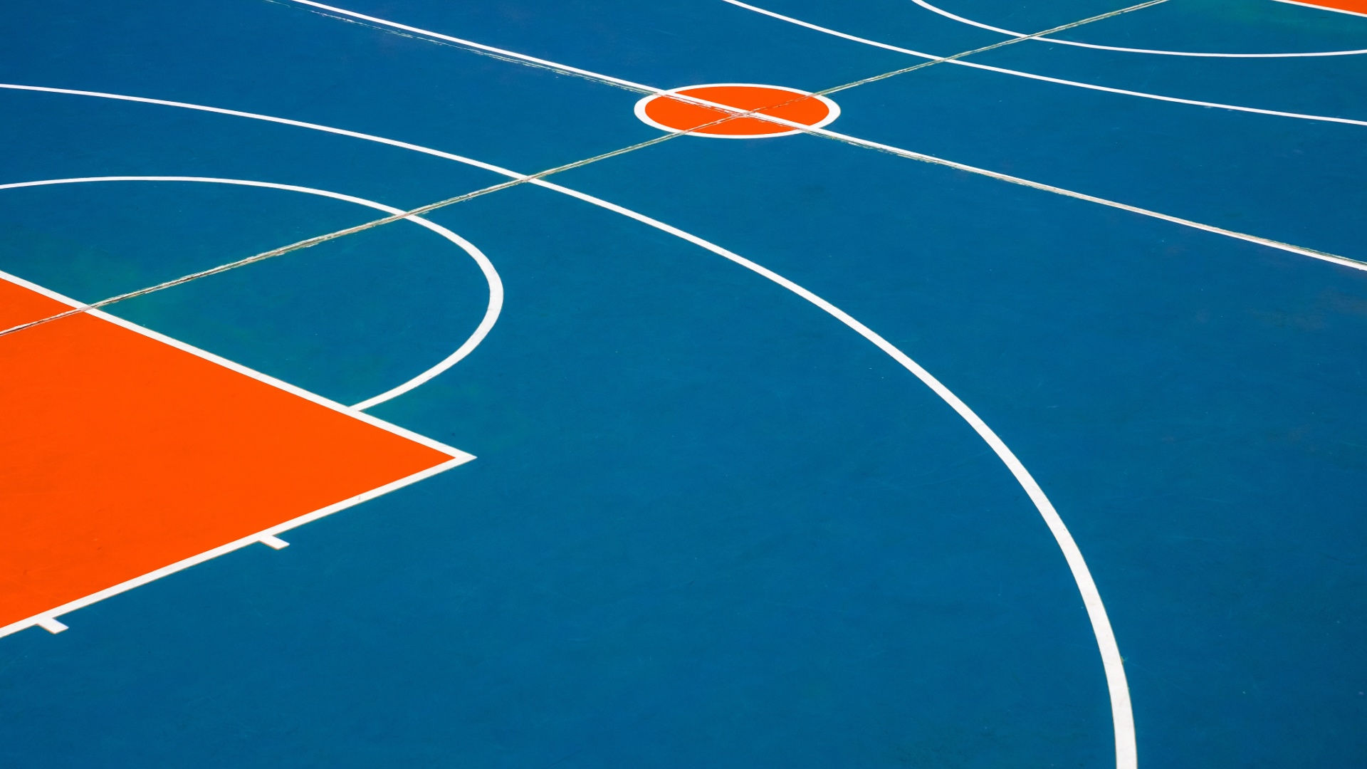 Close-up of a colorful outdoor basketball court with blue and orange markings