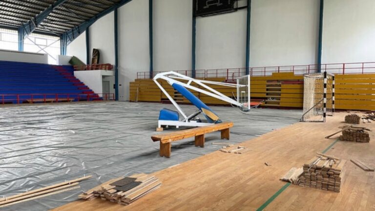 Indoor sports arena under renovation with basketball hoop and seating